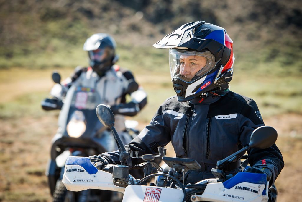 The executive director of BDR, Inna Thorn, rides on a dirt road with others following. Her helmet is equipped with Sena 50S.